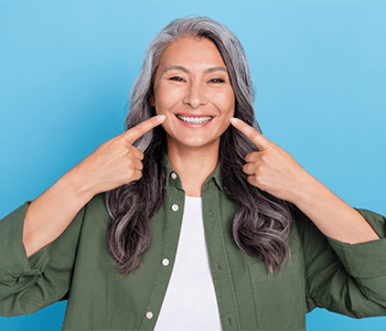 Happy gray-haired woman pointing at her teeth