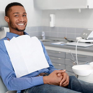 Smiling man sitting in dental chair with hands folded