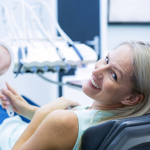 Woman leaning back in dental chair smiling