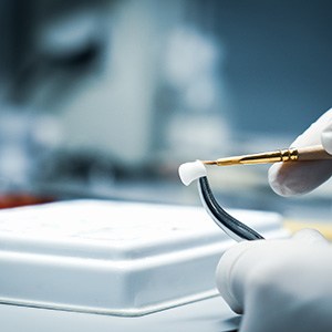 A lab technician processing a dental crown