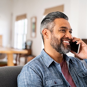 Smiling man talking on cell phone at home